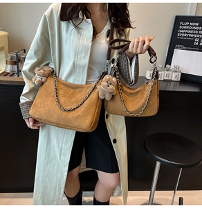 Detail of brown suede crossbody bags in large and small sizes with silver chains