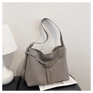 Detail shot of grey frosted leather bucket bag with buckle strap on a leather seat