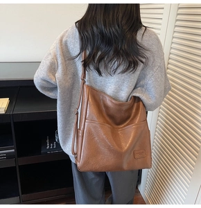 Detail of brown leather tote bag featuring V-shaped stitching and side functional zipper