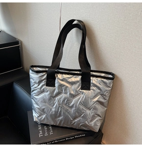 Detail of silver quilted tote bag with metallic finish and black wide fabric straps