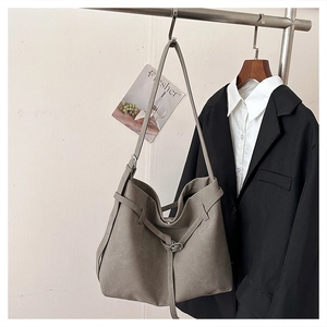 Detail of grey frosted leather tote bag hanging in a minimalist fashion wardrobe setting