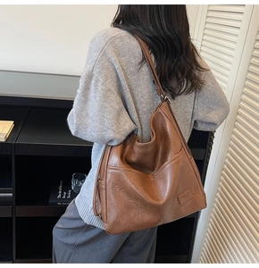 Detail view of large brown faux leather tote bag with side pockets and smooth texture