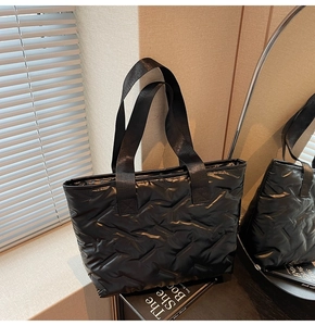 Detail of black quilted tote bag with glossy finish and wave texture in modern setting