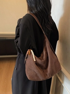 Brown suede hobo shoulder bag with beaded charm accessory shown in a studio setting