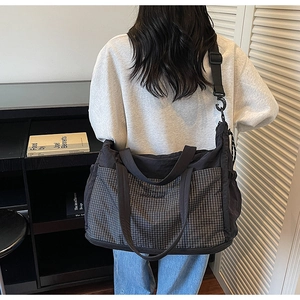 Detail view of large capacity crossbody tote bag with grey plaid and black nylon design