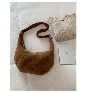 Detail view of brown suede croissant shoulder bag showing soft texture and stitched seams