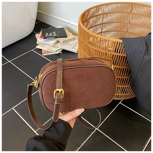 Detail of dark brown matte leather crossbody bag with gold zipper and smooth trim