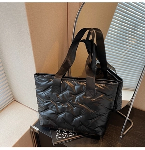 Close-up of black quilted puffer tote bag with V-shaped stitching and wide nylon handles