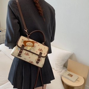 Détail du sac bandoulière crème avec motifs de chiens de dessin animé et ours en peluche
