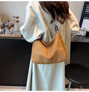 Braune Wildleder Hobo-Tasche mit silberner Kette in der Seitenansicht an der Schulter
