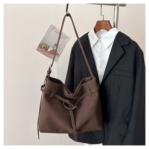 Detail of dark brown matte tote bag featuring metal ring buckle and decorative strap