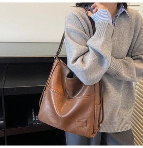Detail of vintage brown leather tote bag with embossed fashion label and metal zipper