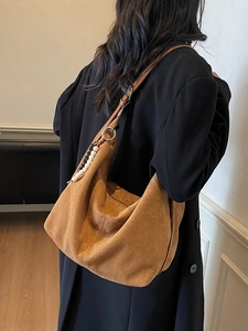 Brown faux suede half-moon hobo bag with colorful bead tassel on a black blazer