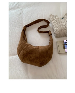 Detail of a brown suede crescent bag with stitching on a cozy white texture
