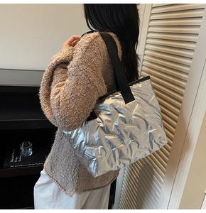 Detail view of large silver tote bag with quilted texture and black woven strap