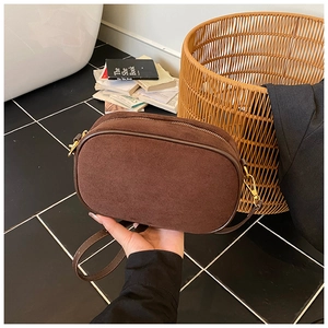 Detail of dark brown suede crossbody bag showing the zipper and golden metal clasp