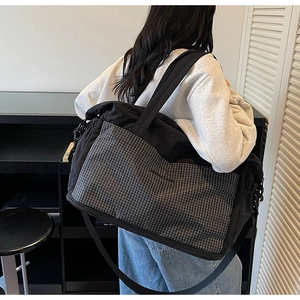 Detail of black travel tote bag with grey checkered pocket and Urban Label text branding