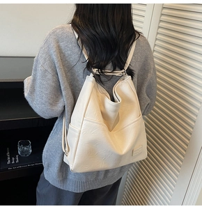Detail of minimalist beige faux leather backpack with adjustable straps and side pockets