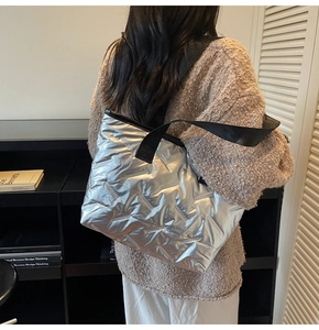 Detail view of the silver quilted tote bag featuring metallic finish and wide black straps