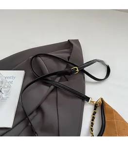 Detail of brown suede crossbody bag with diamond quilting and chain strap shoulder strap