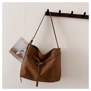 Detail of a brown frosted leather shoulder bag with decorative belt buckle on hooks