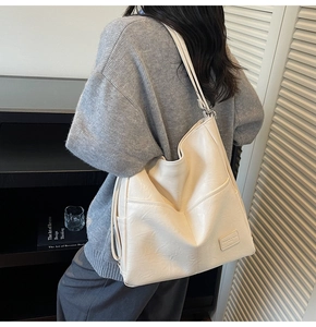 Detail of creamy white faux leather tote bag showing side pocket and textured surface