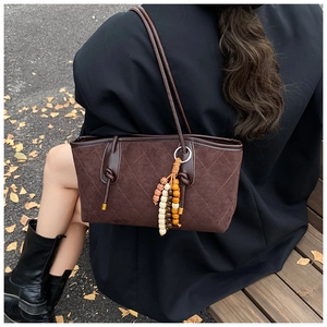Detail of dark brown quilted suede shoulder bag with beaded fringe tassel and dual straps