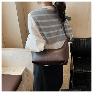 Detail of dark brown leather crescent bag with vertical stitching and knotted shoulder strap
