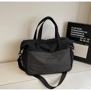 Close-up of black nylon travel tote with checkered pocket on a marble surface