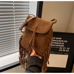 Gros plan d'un sac bandoulière en daim marron avec de longues franges et des pompons