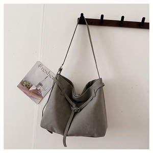 Close-up of matte suede hobo bag featuring leather buckle drawstring and slim shoulder strap