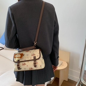 Détail du sac bandoulière crème avec motifs de chiens et charmant pendentif en peluche