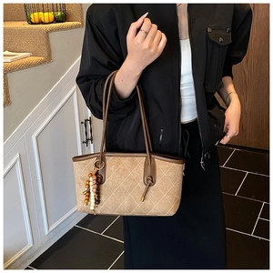 Detailed shot of brown quilted tote bag with suede texture and wooden bead charm accessory