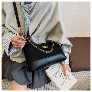 Detailed close-up of a quilted black crossbody bag with metal chain and turn-lock
