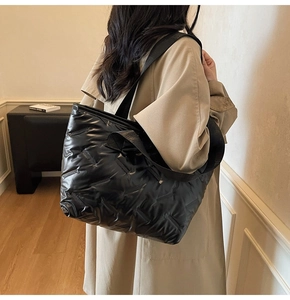 Detailed shot of a black quilted tote bag with large diamond stitching and wide strap