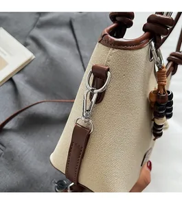 Détail d'un sac seau en toile avec bordure en cuir, anneau en D et breloque en perles