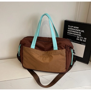 Detail of a large nylon travel tote with vintage plaid pockets and blue handles