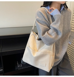 Detail view of cream oversized tote bag with soft PU leather texture and dual front pockets
