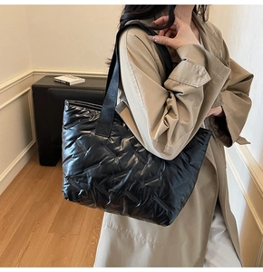 Close-up of black quilted puffer tote bag with glossy finish and durable woven straps