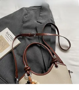 Détail du sac cabas en toile avec garniture en cuir marron et breloques en perles de bois