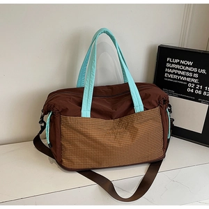 Detail of contrast stitching, plaid pocket, and adjustable strap on large tote bag