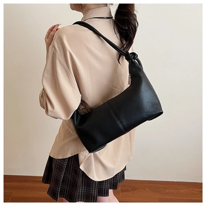 Detail of minimalist black hobo bag with knotted shoulder strap worn by a model