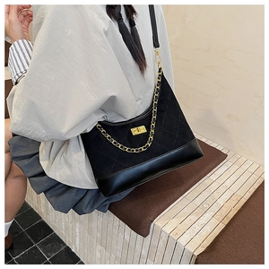 Detail of black quilted shoulder bag with matte leather finish and gold twist lock