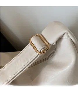 Detail of adjustable cream leather shoulder strap with premium gold metal buckle