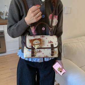 Vue détaillée du sac à main crème avec imprimés de chiots et charm d'ours en peluche