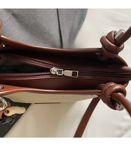 Vue détaillée de la fermeture éclair argentée sur un sac seau en toile et cuir bicolore