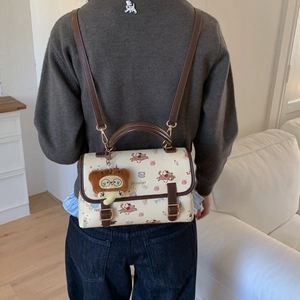 Vue détaillée du sac vintage crème avec imprimé chiot rouge et breloque ours peluche