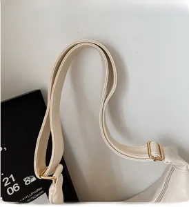 Detail of wide adjustable shoulder strap and gold hardware on cream dumpling bag