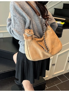 Caramel brown suede hobo bag with chunky chain strap and plush bear charm shown on model
