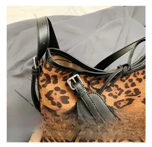 Detail of leopard print tote featuring black leather trim and silver metal buckle